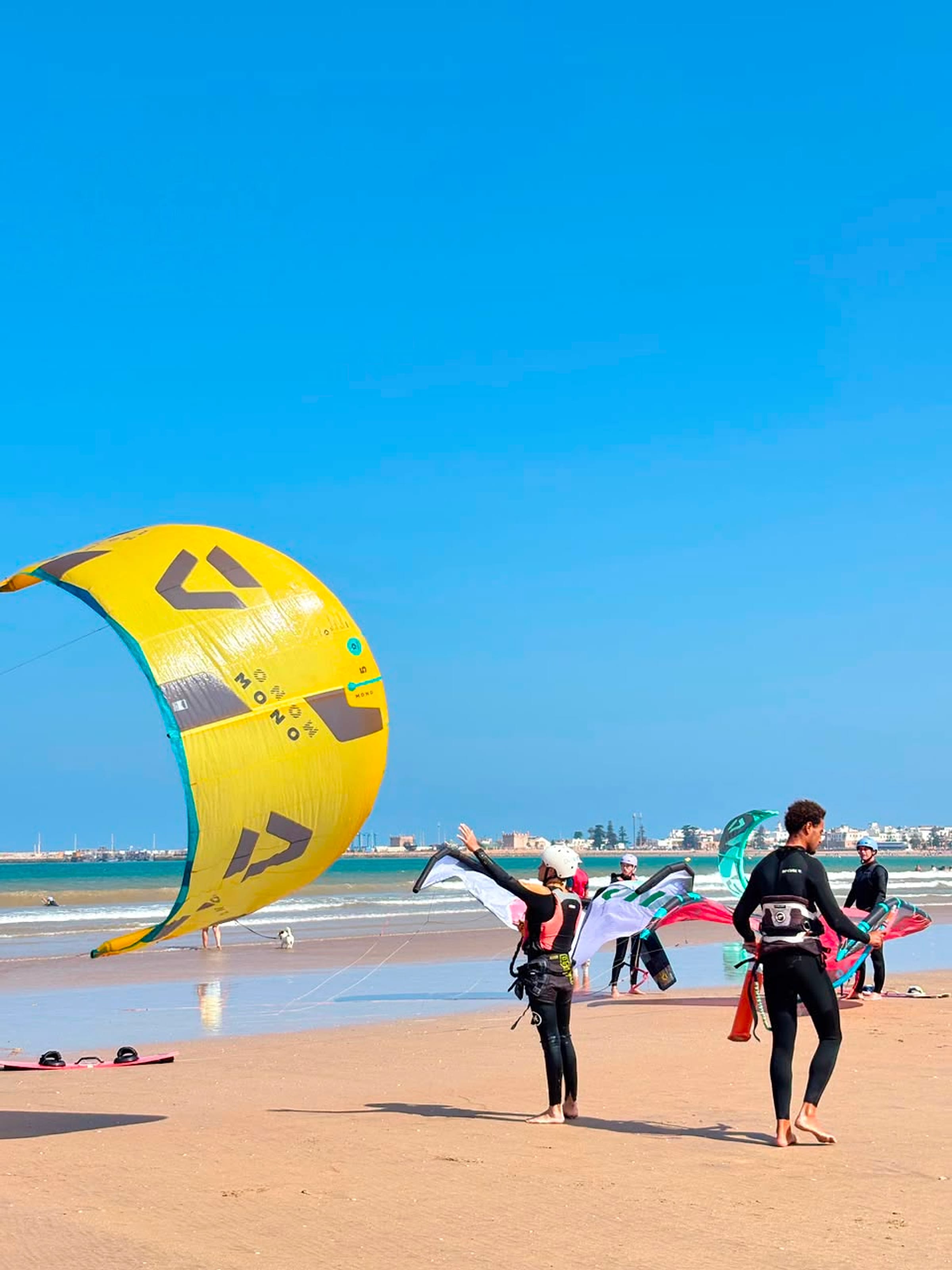 A large yellow kitesurf kite on an open beach.
