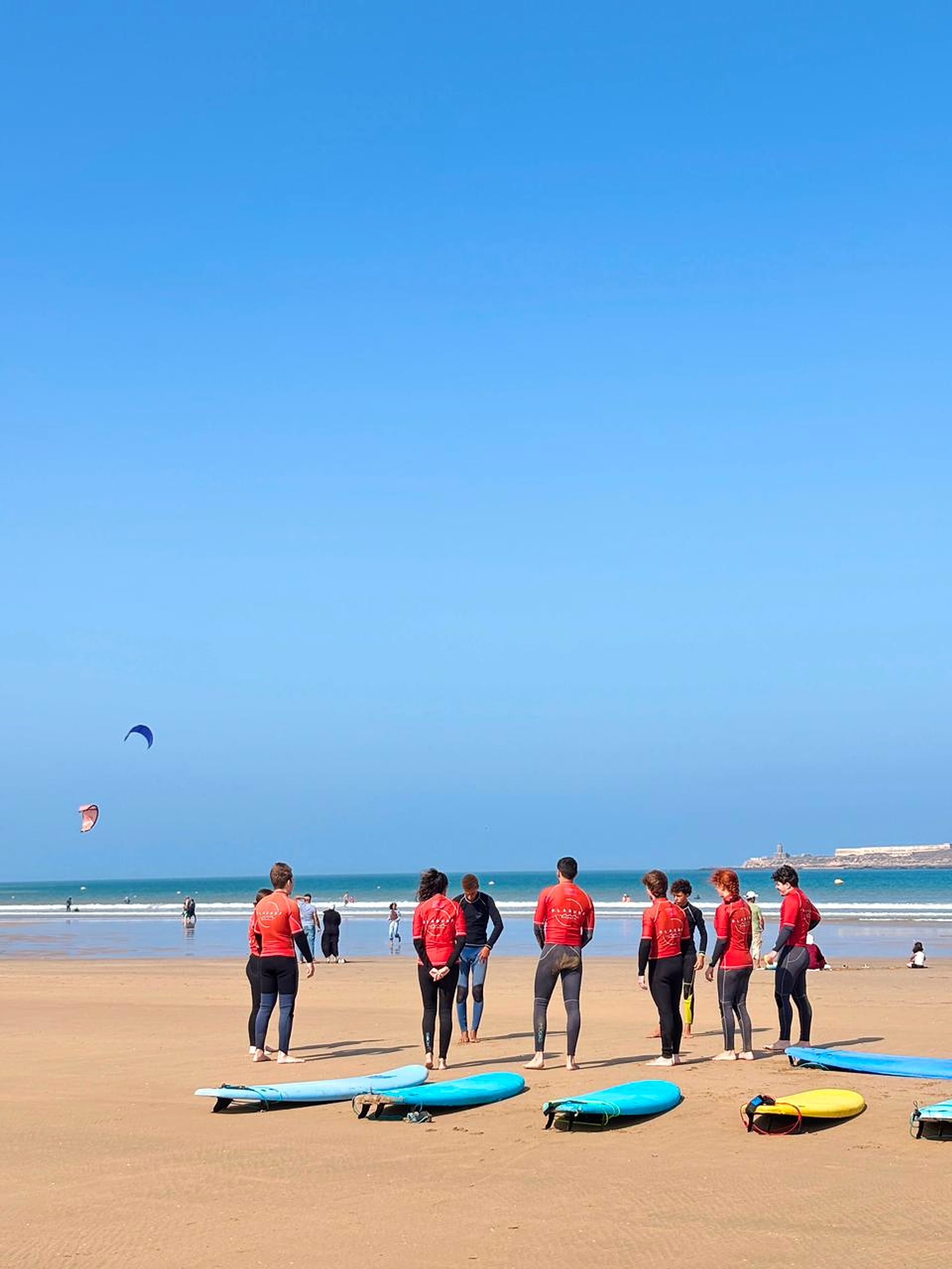 A surf group gathers with boards for a beach briefing in Essaouira.