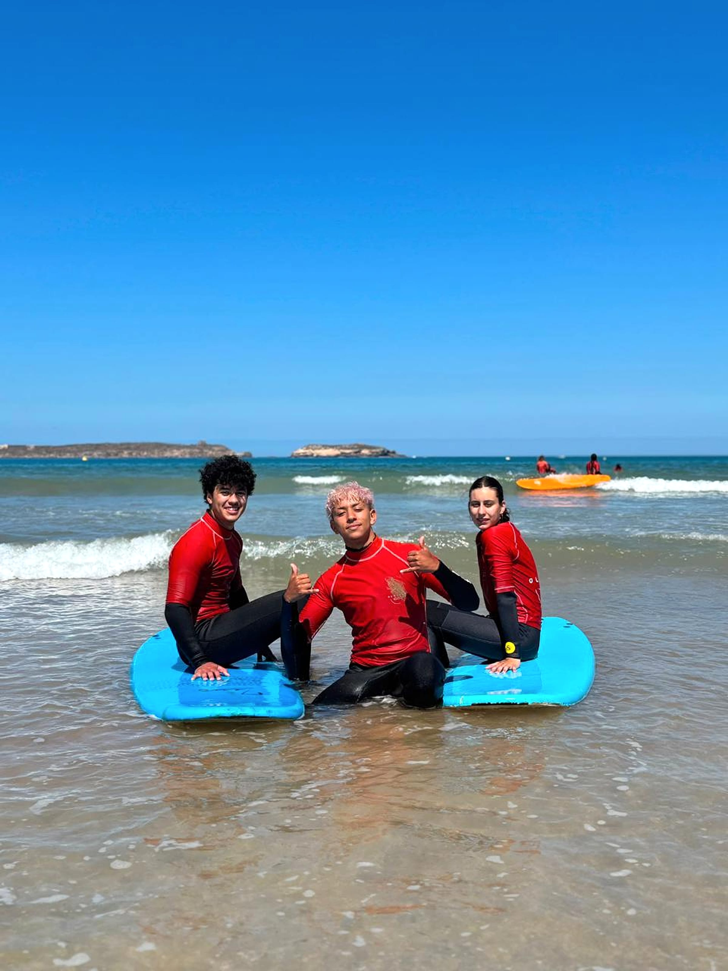 Surf students stand together with blue boards on Essaouira beach.