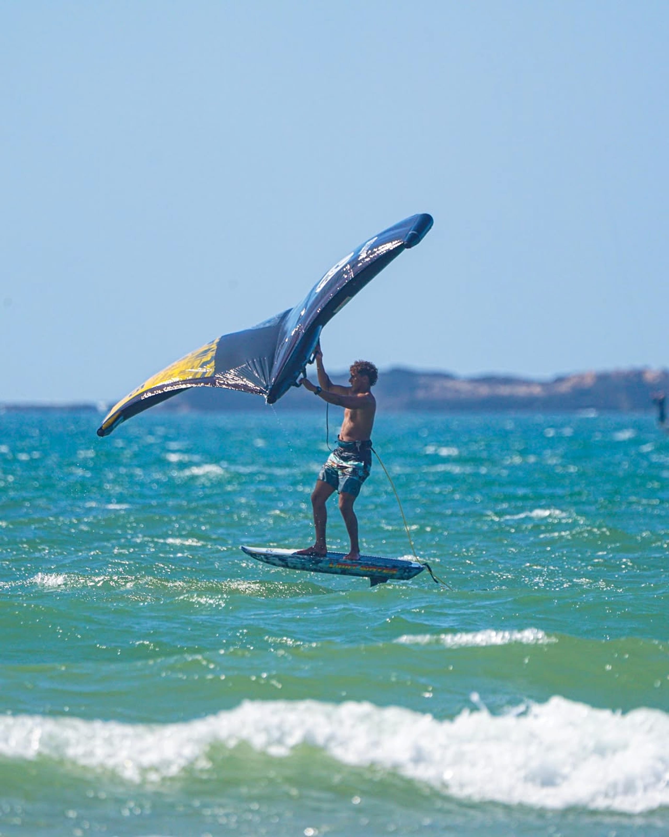 A rider controls a wingfoil wing above the water.