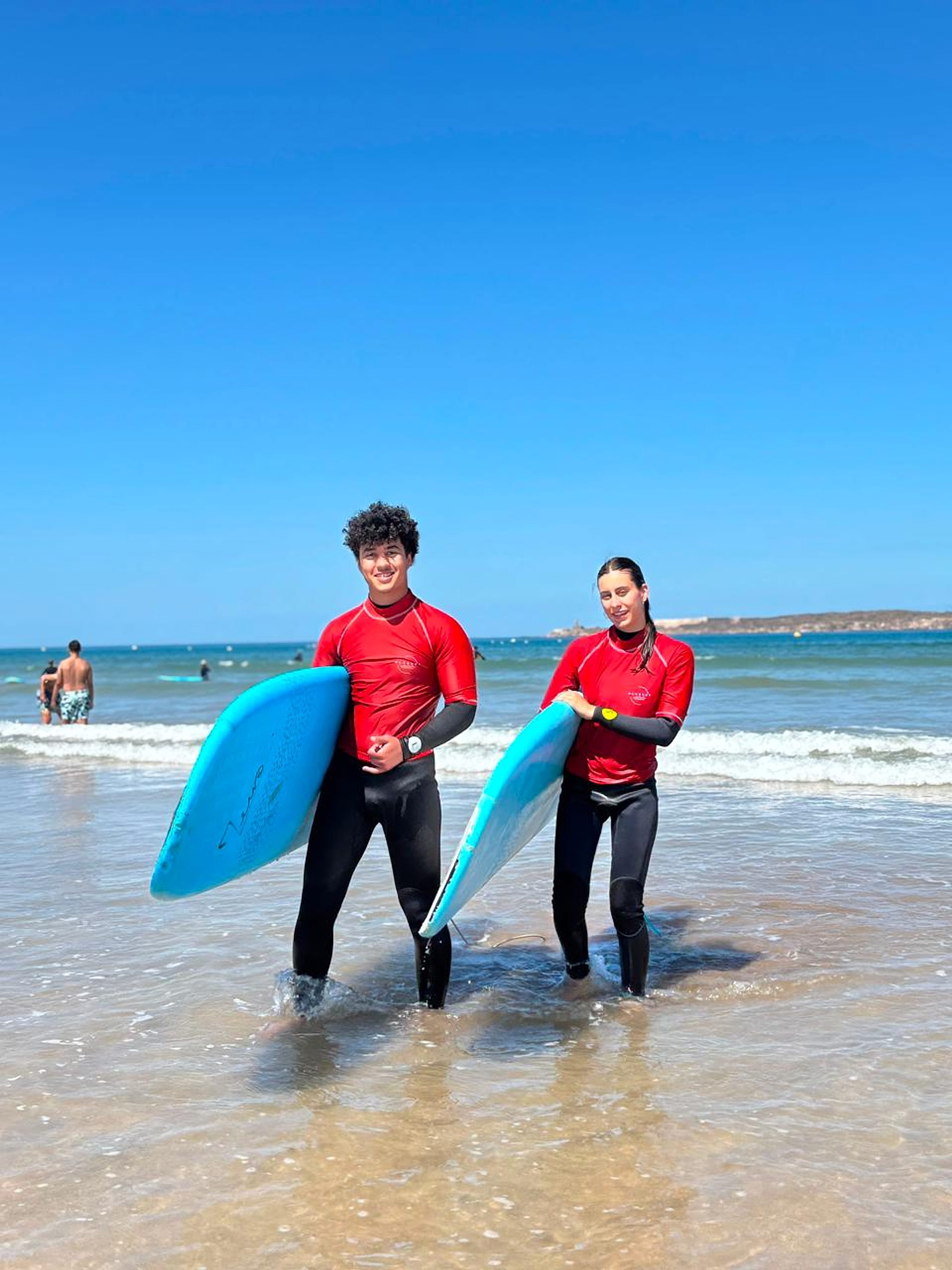 Surfers prepare blue lesson boards on the beach in Essaouira.