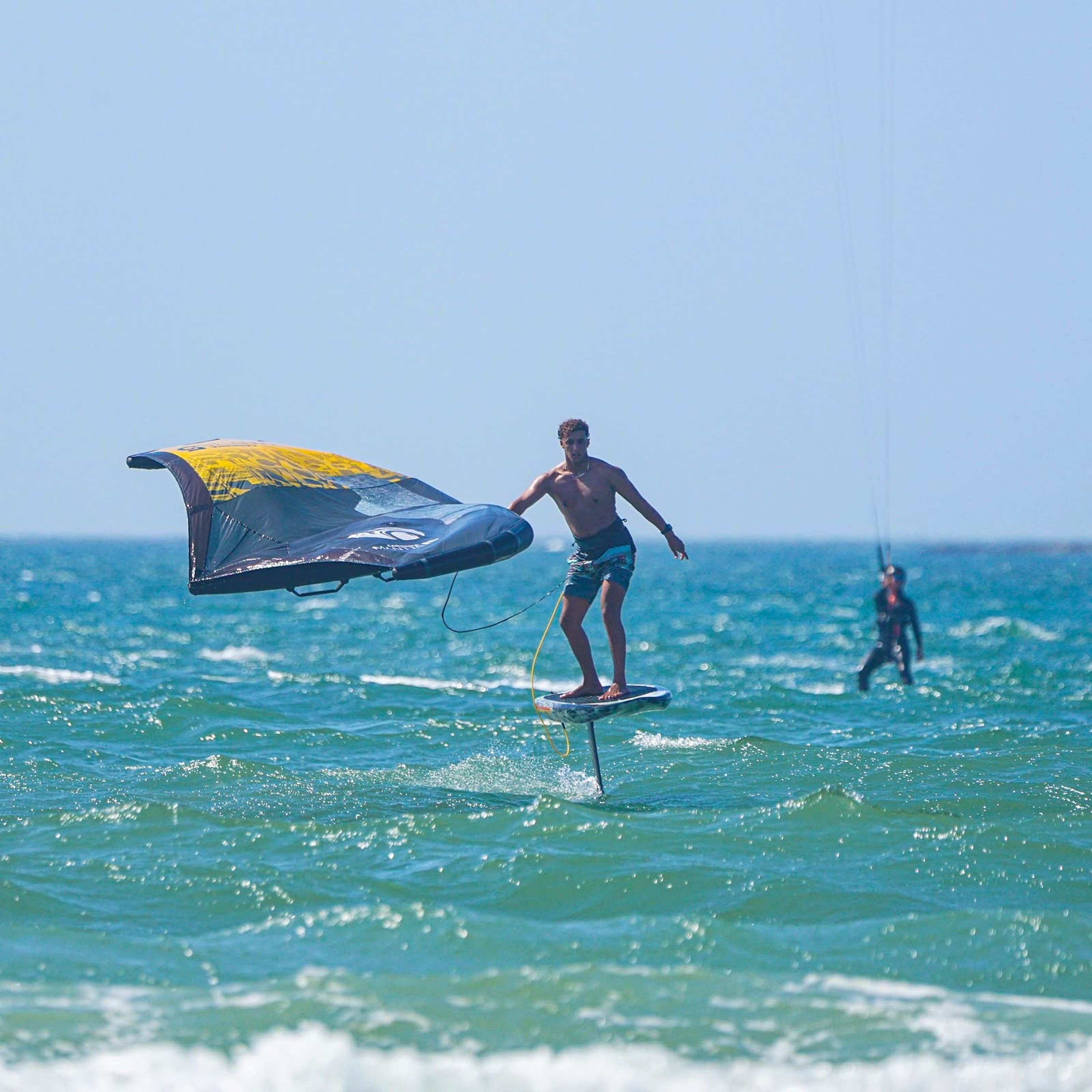 A wingfoil rider glides above choppy water.